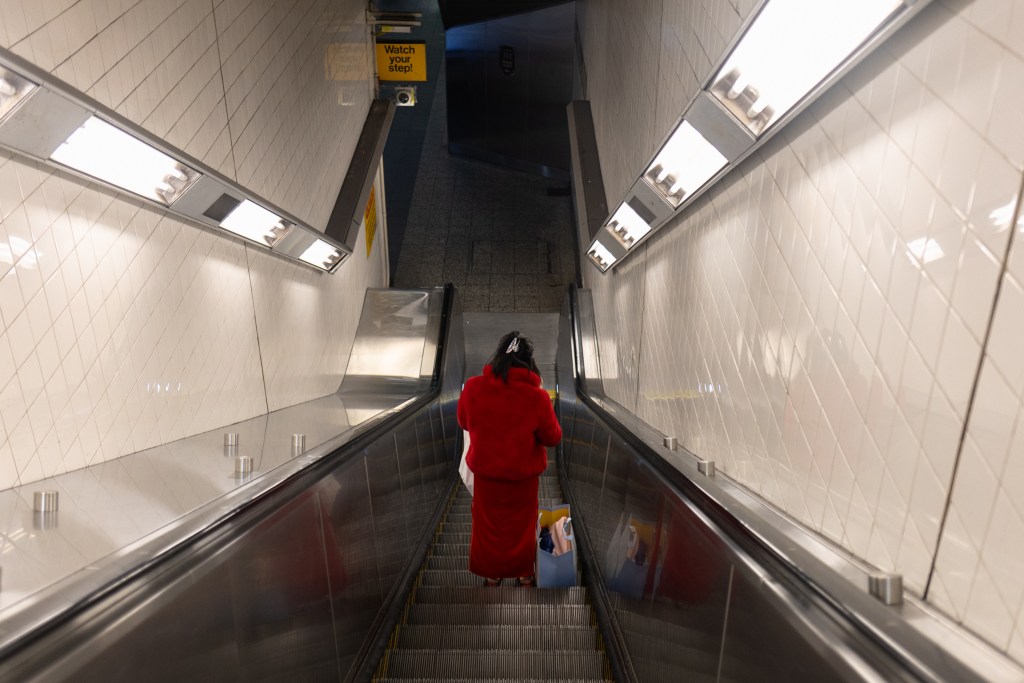 A subway commuter descends an escalator at the Flushing 7 train station,