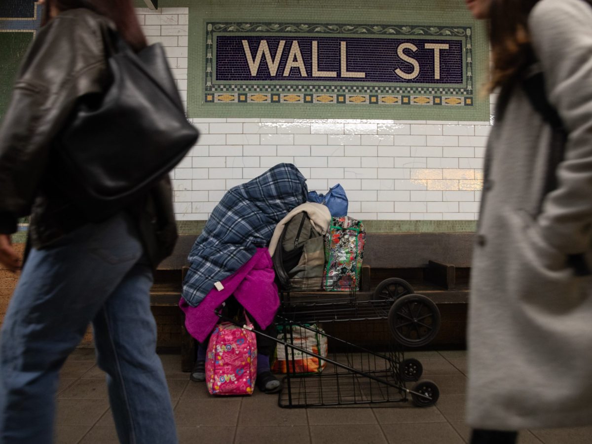 A homeless person sleeps at the Wall Street station during a weekday.