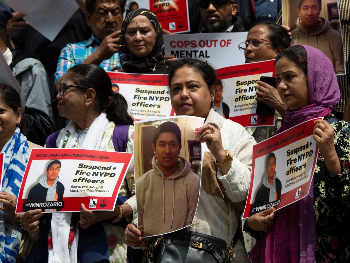 Supporters of Win Rozario’s family hold up signs and pictures at City Hall, May 8, 2024.
