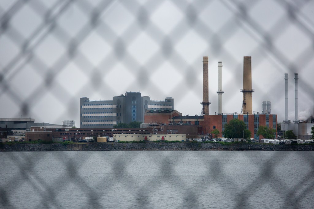 Rikers Island is visible through a fence at the now-shuttered shuttered Vernon Bain jail barge.