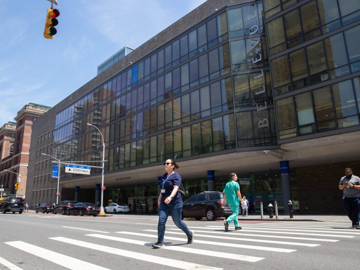 Health-care workers walk across First Avenue outside Bellevue Hospital.