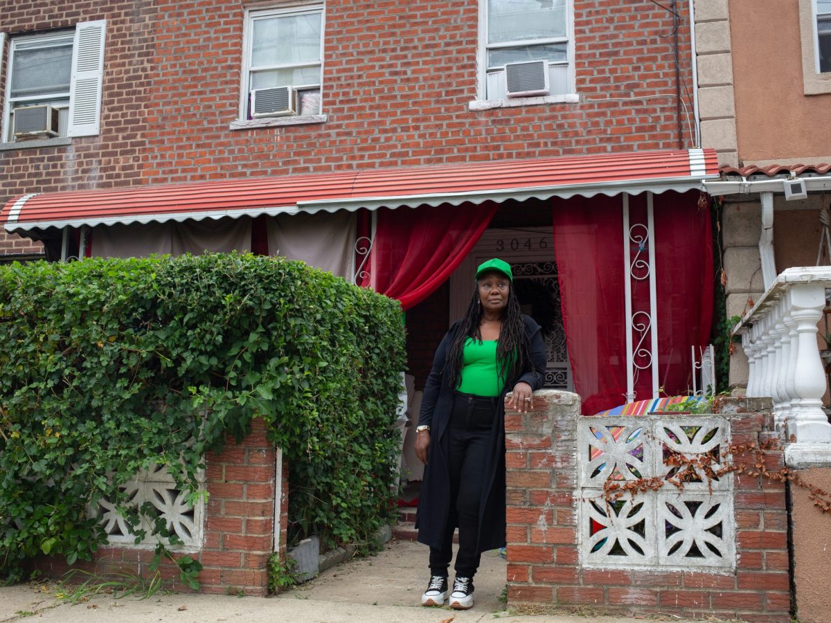 Mae Lee Massey stand in front of her brick row house childhood home in The Bronx.