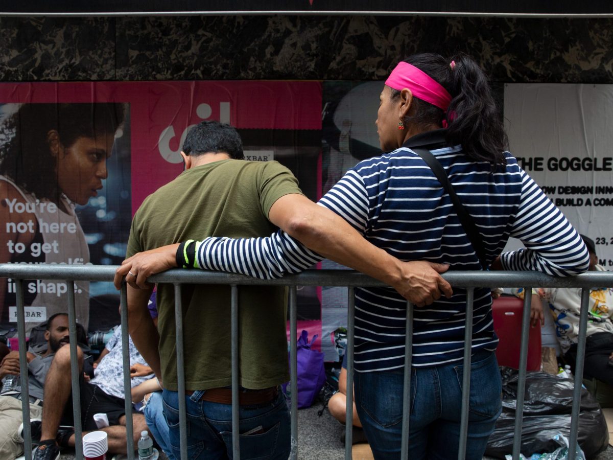 A migrant couple waits in line outside the Roosevelt Hotel shelter.