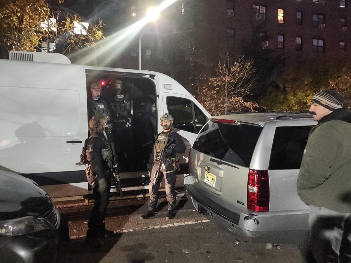 Department of Homeland Security agents hold rifles while wearing tactical gear during an early-morning immigration raid in Jackson Heights