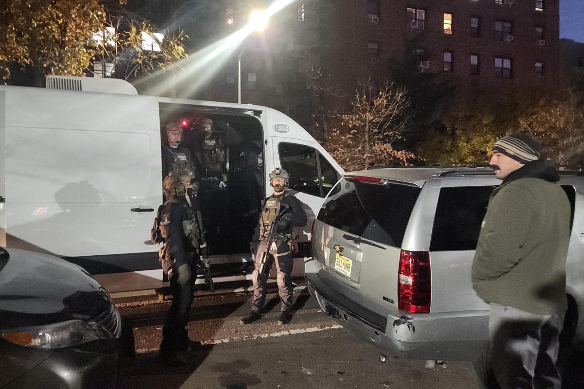 Department of Homeland Security agents hold rifles while wearing tactical gear during an early-morning immigration raid in Jackson Heights