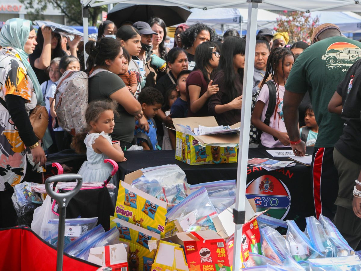 A crowd of people wait for free snacks as part of a back to school give away at Fordham Plaza.
