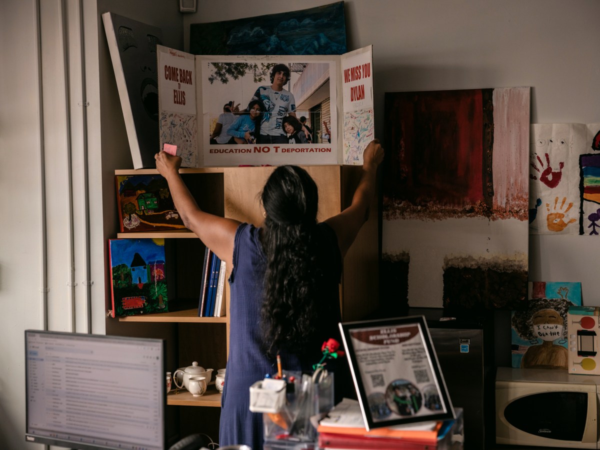 Norma Vega, founding principal at ELLIS Prep, places a poster dedicated to Dylan Lopez Contreras on a shelf in her office.